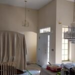 Interior house painting project in Philadelphia showing a living room with vaulted ceilings, large windows, and a chandelier.