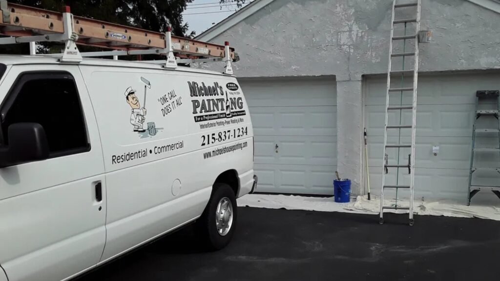 Exterior house painting in Philadelphia with ladders and preparation work on a two-car garage.