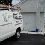 Exterior house painting in Philadelphia with ladders and preparation work on a two-car garage.