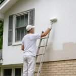 Painter working on a stucco home exterior in Montgomery County, PA.